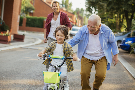 Jeune garçon apprenant à conduire un vélo avec l'aide de son grand-père et de son père